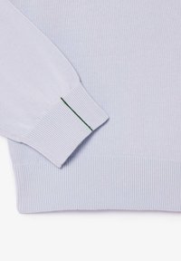 Suéter de punto azul claro con puños y dobladillo acanalados, y un pespunte verde en el puño para añadir detalle.