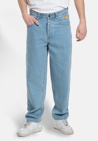 Light blue denim jeans with a loose fit, standard five-pocket design, stitched detailing, and a small orange logo on the waistband.