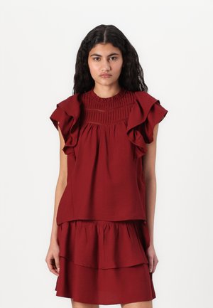 Top rosso senza maniche con spalle arricciate, scollatura arricciata testurizzata e design a strati. Realizzato in un tessuto leggero.