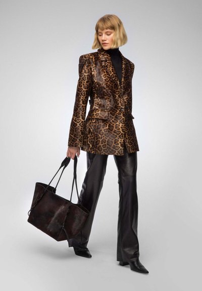 Leopard-print blazer with a glossy finish, paired with black leather pants and a dark tote bag. Model stands in a neutral background.