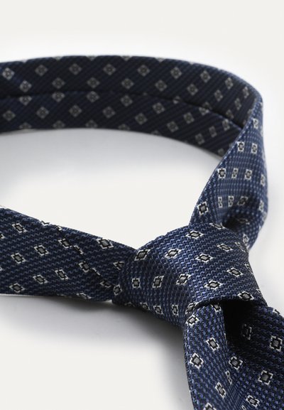 Cravate bleu marine avec un motif texturé comportant de petites formes de diamant argentées. Fabriquée en tissu tissé, elle possède un nœud de cravate standard.