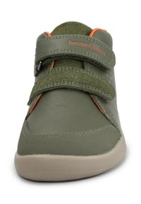 Zapatos de cuero verdes con dos correas de velcro, suela gris, detalles en naranja y tejido texturizado alrededor del tobillo para soporte y comodidad.
