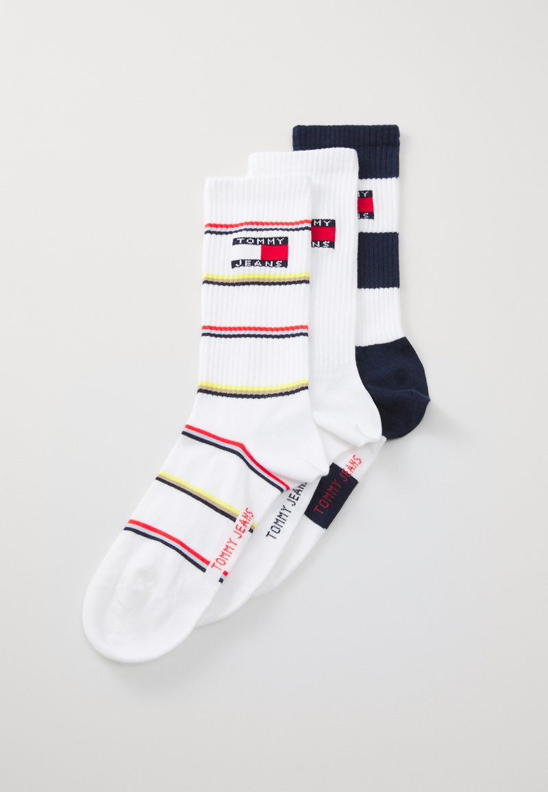 Three pairs of socks: one white with colorful stripes, one white with navy stripes, and one solid navy. Ribbed texture, logo detailing.