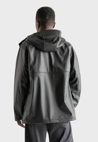 Zwarte waterdichte jas met een capuchon, gladde textuur en zichtbare stikseldetails. Ontworpen voor een relaxed fit, geschikt voor gebruik buitenshuis.