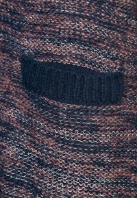 Suéter de punto con un patrón jaspeado en tonos de marrón y azul marino, con un bolsillo texturizado en la parte delantera de material azul marino a juego.