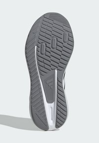 Suola di scarpa sportiva grigia e bianca con motivo antiscivolo testurizzato e logo triangolare Adidas al centro.