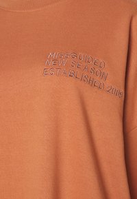 Oranžová mikina s výšivkou "Missguided New Season Established 2009" ve tmavší nitce. Měkký materiál, klasický střih s kulatým výstřihem.