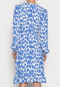 Vestido de leopardo azul y blanco con mangas largas, cintura ajustada y dobladillo con volantes. Hecho de una tela ligera con una textura suave.