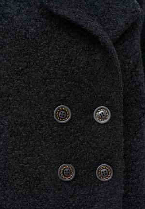 Czarny teksturowany płaszcz z grubego, plecionego materiału, ozdobiony czterema błyszczącymi guzikami z ozdobnym wzorem w postaci liny. Kołnierz jest złożony, co dodaje szczegółów.