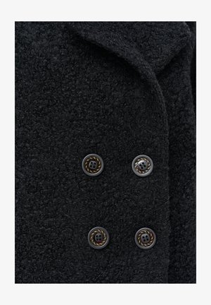 Czarny teksturowany płaszcz z grubego, plecionego materiału, ozdobiony czterema błyszczącymi guzikami z ozdobnym wzorem w postaci liny. Kołnierz jest złożony, co dodaje szczegółów.