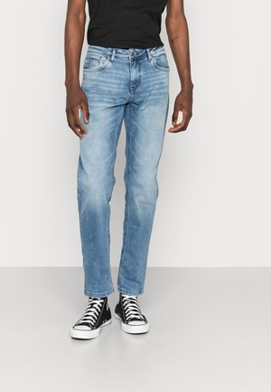 Lichtblauwe denim jeans met een rechte pijpdesign, met een klassieke vijf-pocketstijl en vage versleten patches. Gepaard met zwarte hoge sneakers.