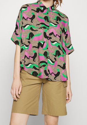Camicia a manica corta dai colori vivaci con forme astratte in rosa, verde, nero e bianco su uno sfondo beige a pois.