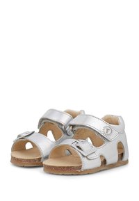 Silberne Leder-Sandalen mit offenem Zehenbereich, zwei verstellbaren Riemen und einer strukturierten braunen Sohle. Verfügt über Aussparungen und ein Detail mit einer Metallschnalle.