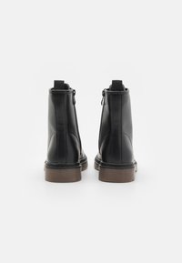 Sorte lær ankelstøvler med en glat finish, rund tå, glidelåser på siden, dragere og brune gummisåler. Minimalistisk design, ingen synlige mønstre.