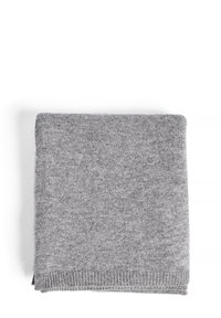 Couverture tricotée gris clair, pliée soigneusement. Texture douce, bordée d'un subtil bord côtelé. Couleur uniforme sans motifs ni hardware visibles.