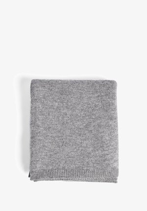Couverture tricotée gris clair, pliée soigneusement. Texture douce, bordée d'un subtil bord côtelé. Couleur uniforme sans motifs ni hardware visibles.
