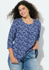 Granatowy top w kwiatowy wzór z rękawami do łokcia, miękki materiał, okrągły dekolt i luźne dopasowanie, zestawiony z postrzępionymi dżinsami.