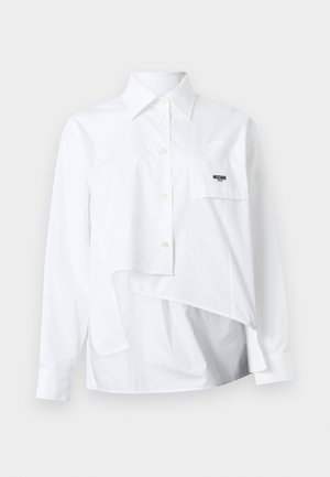 Bijela majica s dugim rukavima s asimetričnim rubom i prednjim džepom na kojem se nalazi mali crni logo "Moschino" na čistoj pozadini.