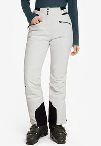 Pantalones de esquí en gris claro con detalles en negro, que cuentan con una cintura alta, bolsillos con cremallera y un diseño ajustado. Fabricados con un material duradero y resistente a las inclemencias del tiempo.