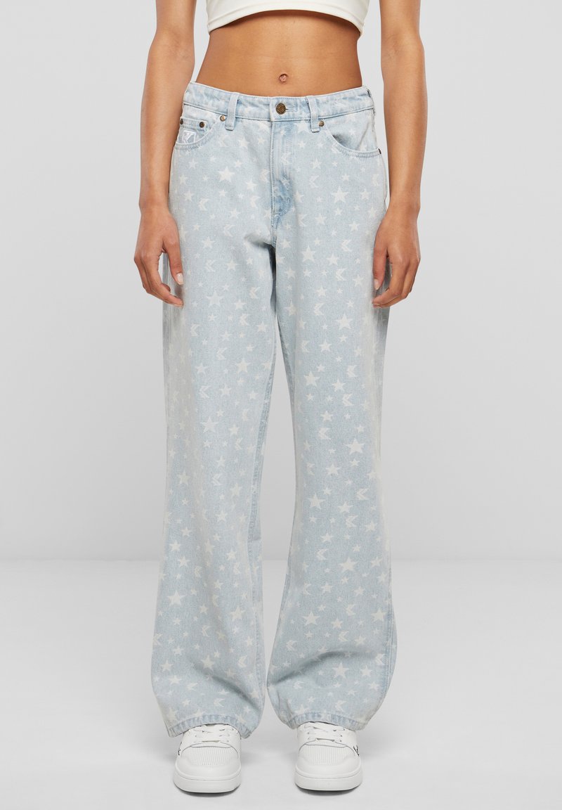 Jean large bleu clair avec un motif d'étoiles blanches sur l'ensemble. Design classique à cinq poches avec fermeture à bouton et coutures apparentes.
