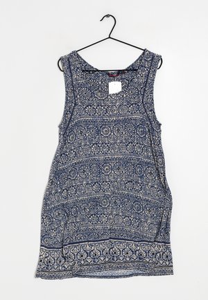 Ärmelloses blau-weiß gemustertes Kleid mit floralen und geometrischen Mustern, das an einem schwarzen Kleiderbügel vor weißem Hintergrund hängt.