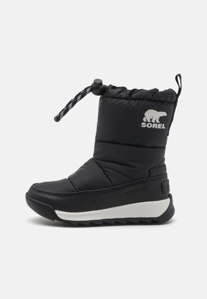 Botte d'hiver isolée noire avec semelle blanche, cordon de serrage ajustable à la cheville et logo ours blanc avec le texte "SOREL" sur le côté.