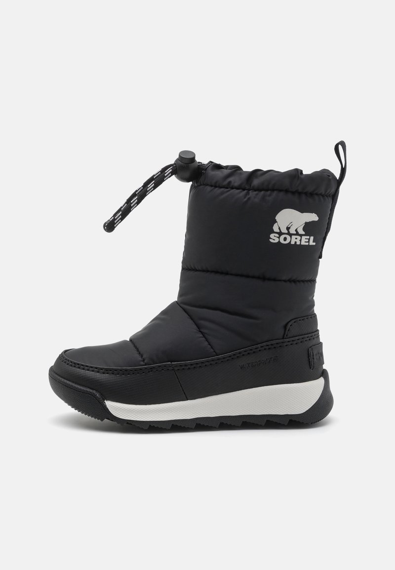 Botte d'hiver isolée noire avec semelle blanche, cordon de serrage ajustable à la cheville et logo ours blanc avec le texte "SOREL" sur le côté.