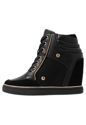 Baskets compensées noires avec une tige en cuir lisse, fermeture éclair métallique dorée et accents dorés. Présente une semelle intermédiaire texturée et un design à lacets.