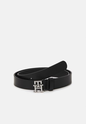 Ceinture en cuir noir enroulée avec boucle logo double T en argent sur fond blanc.