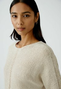 Strickpullover in einem hellbeigen Farbton mit Rundhalsausschnitt, ausgestattet mit horizontalen Streifen und einem strukturierten Gewebe. Einfaches Design, Ärmel in Ellbogenlänge.