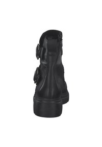 Svarta läderankelboots med dragkedjor, med tre spännen på sidorna. Sålen är tjock med vertikal räfflad textur.