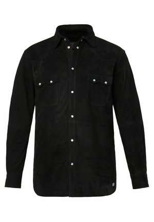 Camisa de ante negro con cierre de botones en la parte delantera, dos bolsillos en el pecho, cuello puntiagudo y mangas largas. Presenta botones de metal y una textura suave.