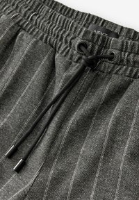 Graue Herringbone-Jogginghosen mit einem vertikalen Streifenmuster, elastischem Bund und schwarzem Zugband mit Plastik-Aglets.