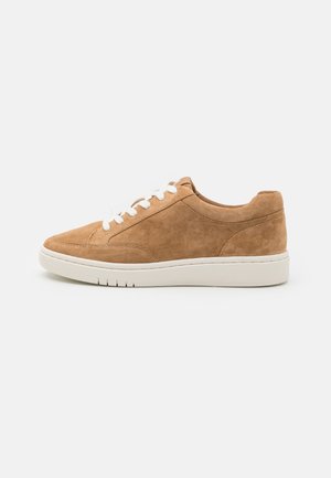 Legerner hellbrauner Wildleder-Sneaker mit weißen Schnürsenkeln und dicker weißer Gummisohle, seitlich auf schlichtem Hintergrund abgebildet.