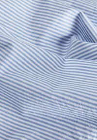 Ljusblått tyg med tunna vita ränder, visar en jämn yta och lätt veckning. Tyget är mjukt och lätt.