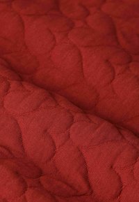 Rode gestikte stof met een textuurpatroon van gebogen vormen, met een zachte en gladde afwerking. Eenvormige kleur zonder zichtbare hardware.