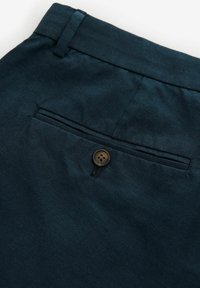 Navyblaue Hose mit glatter Textur, ausgestattet mit einer Gesäßtasche mit einem braunen Knopf und einem geraden Bunddesign.