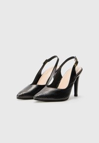 Décolleté nera con un motivo a pelle di serpente testurizzato, punta affilata e tacco a stiletto. Dettaglio della fibbia dorata sulla cinghia.