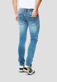 Jeans skinny-fit in denim azzurro chiaro, con due tasche posteriori con cuciture a contrasto e vita a metà altezza. Abbinati a sneakers multicolore.