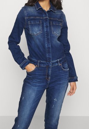 Denim jumpsuit in dark blue featuring two chest pockets, a button-up front, and a fitted waist with distressed detailing on the legs.