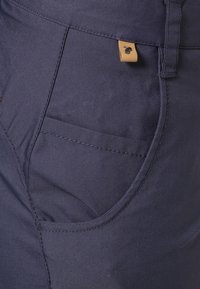 Navy blue cotton pants featuring a side pocket and a small tan logo patch. The fabric has a smooth texture with subtle diagonal lines.