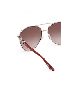 Ochelari de soare aviator cu gradient maro, cu ramă metalică argintie și brațe din plastic burgundy. Logo gravat pe braț.