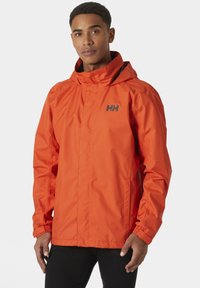 Chaqueta impermeable de un brillante color naranja, con capucha, cierre de cremallera y puños elásticos. Incluye un logotipo negro en el pecho y bolsillos laterales.