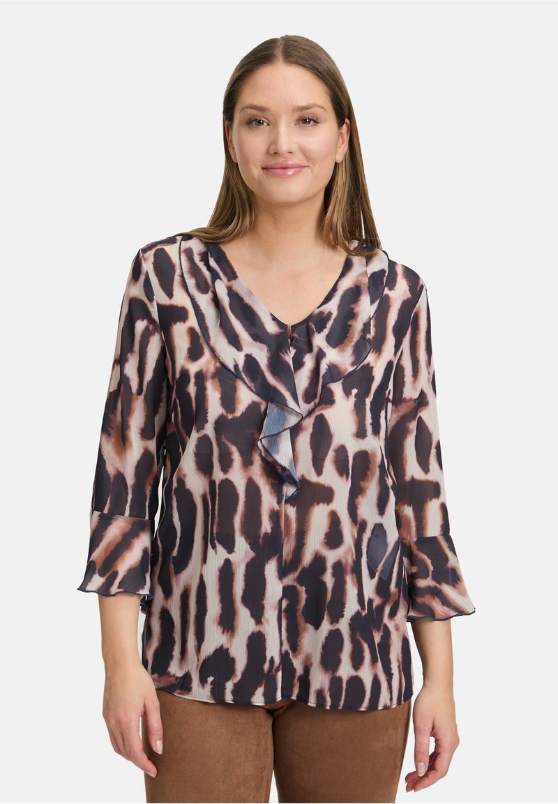 Blouse fluide à imprimé animal, mettant en valeur des détails en volants superposés, un décolleté en V, des manches trois-quarts et une texture soyeuse dans des tons taupe et foncés.