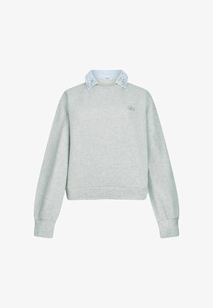 Harmaa kevyt collegepaita, jossa on lyhennetty muotoilu, sinivalkoiset raidat kauluksessa ja pieni logo vasemmalla puolella.