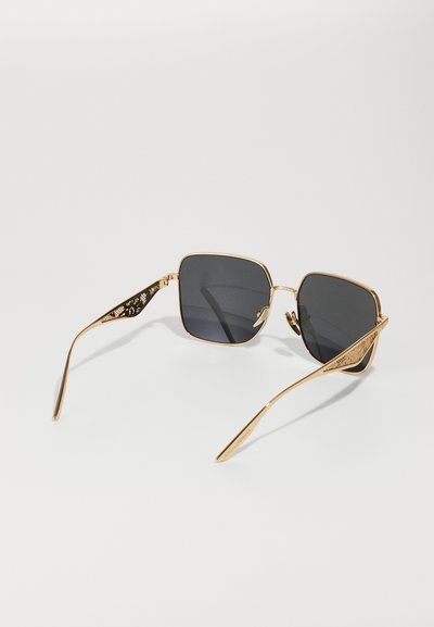 Gafas de sol con montura de metal dorado, lentes oscuros en forma cuadrada y brazos detalladamente decorados para añadir textura y diseño.