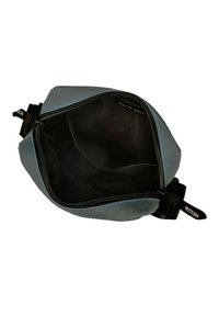 Blaue Stofftasche mit Reißverschluss, die eine glatte Textur und ein geräumiges, schwarz gefüttertes Innere zeigt. Verfügt über einen seitlichen Riemen mit Logo.