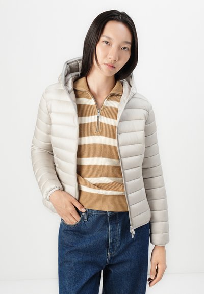 Doudoune gris clair à la coupe ajustée, avec fermeture éclair sur le devant et capuche, superposée à un pull rayé beige et blanc, associée à un jean bleu.