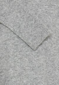 Pulover gri deschis, cu un tricot moale și texturat. Prezintă un manșon pružat la mânecă, creând un aspect confortabil și primitor.