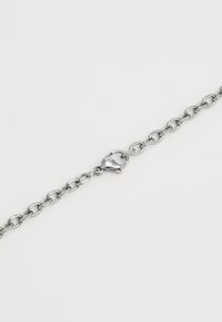 Βραχιόλι από μέταλλο σε ασημί απόχρωση με διασυνδεδεμένους ωοειδείς κρίκους, που διαθέτει κούμπωμα με καβουράκι για ασφαλές κλείσιμο. Λείος υφές.